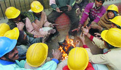 Delhi Metro workers kill the chill at a work site in the Capital