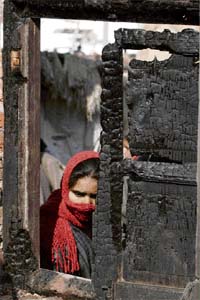 A woman looks at the house where the militant was shot dead by security forces
