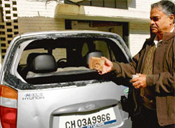 S. L. Soni shows the brick and the smashed rear windowpane of his car outside his residence in Sector 32 in Chandigarh