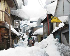 People walking through a snow-covered street in Bhadarwah where the ground floors of the houses were covered with snow following a heavy snowfall in Jammu and Kashmir