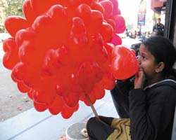 A girl blows heart-shaped balloons to earn her livelihood