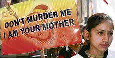 A schoolgirl carries a placard depicting message against female foeticide in a candle light rally orgainsed by the Childrens Welfare Society in Jammu on Friday