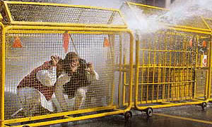 Bharatiya Janata Party activists cover themselves as police officials use a water cannon to disperse a protest against the fuel price hike in New Delhi on Friday.