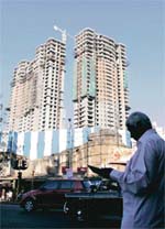 A man reads a newspaper near a construction site in Mumbai on Monday. A booming economy and rising incomes have led to a surge in home and commercial property prices in Indian cities.
