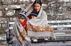A mother shields her children from chill as the weather took a turn after a few days of bright sunshine in Shimla on Wednesday. 