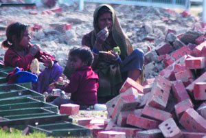 A worker engaged in the dismantling of the Republic Day podium at Raj Path shares her meal with children on Sunday.