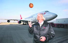 Richard Branson tosses a coconut in front of a Virgin Atlantic Boeing 747 before it embarks on the first test flight using bio-fuel made from coconut oil at Heathrow Airport in London