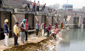 Unmindful of their safety, labourers work on the edge of a waterhead at Maanpur near Ahmedgarh.
