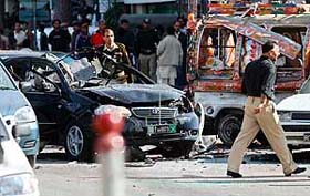 Pakistani security officials examine a badly damaged vehicle after a suicide attack in Rawalpindi