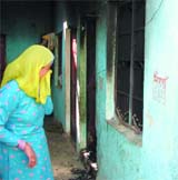 A woman stops in front of the room where four persons died in a fire at Gopal Nagar near Najafgarh in the Capital on Wednesday.