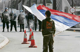A student waves a Serbian national flag in front of the riot police during a march on the main bridge, separating Kosovo Serbs and Kosovo Albanian districts, in protest against Kosovos independence in the ethnically divided town on Friday.