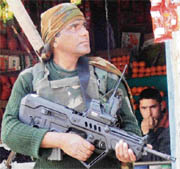 A Kashmir boy looks at an Army personnel who stands guard carrying the latest sophisticated gun procured from Israel in Srinagar on Saturday. The Army authorities are hopeful that these weapons will be more beneficial in their fight against militants.