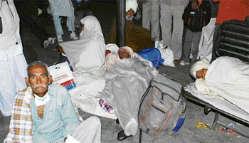 Diwan Chand, a cancer patient, and two other women patients wrapped in blankets wait for a train at the Bathinda railway station to go to Bikaner for treatment