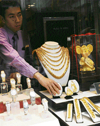 A store assistant arranges gold necklaces for sale at a shop in Hong Kong on Sunday. Gold prices closed on Friday at $995-$995.50 an ounce, up from March 13 close of $987.10-$987.60.