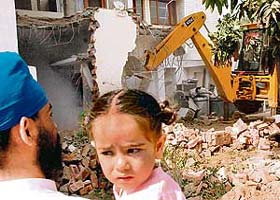 A father and a child watch as the MC squad demolishes a part of their house in Sector 45, Chandigarh