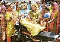 Women of Harijan Basti in Jathlana, Yamunanagar, show liquor bottles and a motor cycle taken away by them from a liquor smuggler on Friday.