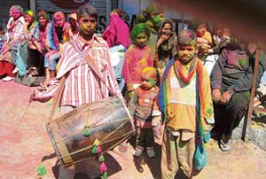 Children smeared with varied colours make merry in a Mandi bazar to celebrate Holi on Friday. 