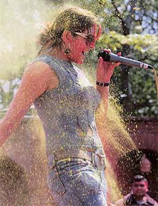 Coloured powder is thrown on singer Agantuk Kharel as she sings during the celebration of Holi in Kathmandu