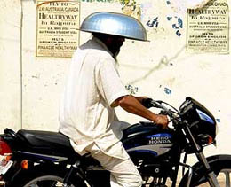 A bike rider wears a steel tub to protect himself from the scorching sun in Rajpura on Wednesday.