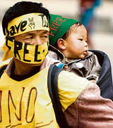 A Tibetan carries his child on his back during a protest in Srinagar on Wednesday.