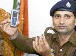 A police officer displays a mobile phone and sim card, which were used to trigger an IED blast, in Srinagar 