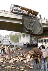 Sweepers clean the crushed pile of beer bottles that fell down on the road after the truck, which was carrying them, overturned on the Jammu flyover on Sunday