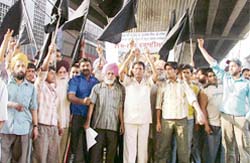 Autorickshaw drivers hold a protest, carrying black flags, at the Clock Tower in Ludhiana