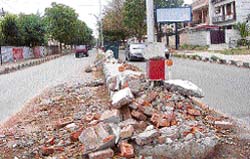 The damaged divider of Phase IX-X poses a threat to motorists. Tribune photo: Vicky Gharu