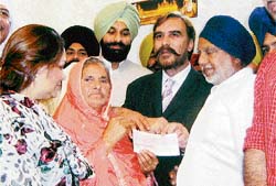 Public relations minister Bikram Singh Majithia along with member of the United Nations Human Rights Councils Advisory Committee Ansar Burney, presents a cheque for Rs 10 lakh to Kashmir Singh and his wife Paramjit Kaur at Nangal Choran village