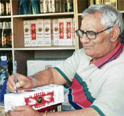 Sat Pal signs a bottle at his liquor vend in Raipur Kalan.