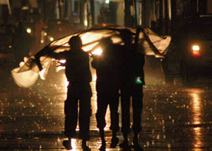 Children try to cover themselves with a plastic sheet during rain in Ludhiana on Saturday night.