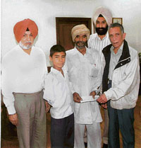 PSEB chairman Y.S. Ratra handing over a cheque to Titu in Patiala on Tuesday.