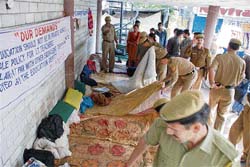 Policemen collect the belongings of fasting computer teachers after they were removed from Gandhi Chowk at Hamirpur