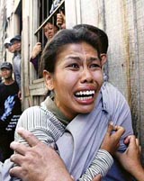A woman cries as she is led away from her burning house in Phnom Penh on Friday.