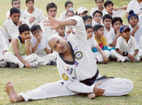 Tony Vohra, grand master black belt, demonstrates fitness tips to budding cricket players of MCM Blue Cap Academy at Sector 36 in Chandigarh on Sunday.
