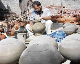With the mercury rising, Satbeer Singh, a potter, makes earthen pots in Karnal on Wednesday.