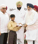 Chief Minister Parkash Singh Badal presents a scholarship certificate to Mangat Singh in Ludhiana.