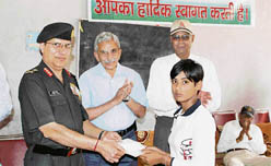 Lt-Gen Avdhesh Prakash gives a kisan vikas patra to a girl child of a martyrs family at a function in Rewari 