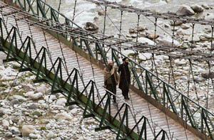 Two men cross a hanging bridge in the border region of Surnakote in Poonch district. The bridge connects two parts of a village which is separated by the river. 