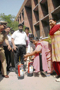 A staff member at Government Model School, Sector 37, Chandigarh, demonstrates the use of equipment to the fire department officials in Chandigarh on Thursday.