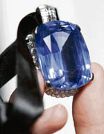 A Sotheby's employee holds a 206.82 carat sapphire pendant set with diamonds and created by the jeweller Cartier in 1951, at the auction house in London on Friday. 