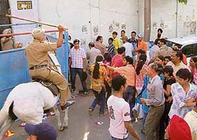 A mounted policeman charges towards a group of youngsters to disperse them from a PCA gate in Mohali