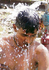 A man takes bath under the hose on a hot summer day at the railway station in Ludhiana.