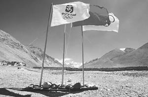Tibetens walk behind flag poles flying the Olympic flag, the Chinese national flag and the official Beijing Olympic Games flag in front of the peak of Mount Everest on the outskirts of Everest Base camp on Monday.
