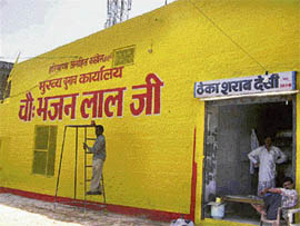 A painter gives final touches to the outer wall of Bhajan Lal's main election office on the Balsamand road in Hisar on Tuesday. Interestingly, a country liquor shop is located in the same building.