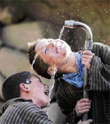 Two boys drinking water from a tap in Bathi-Jalan village, 115 km south of Srinagar, on Sunday.