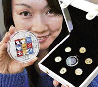 An employee of Japanese money commodity trader Taisei Coins displays a set of Cook Islands' 1/25 ounce gold coins (R) and a five ounce silver coin designed after the popular cartoon character Snoopy to celebrate the 40th anniversary of publication, in Tokyo on Wednesday. The coin will be on sale from Thursday.