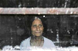 A Kashmiri Pandit woman looks through the window of her house at the Muthi Migrant Camp on the outskirts of Jammu.