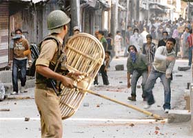 A policeman holds his riot shield as protesters throw stones during a demonstration in Srinagar