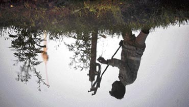 A man is reflected in a canal as he pumps water on the outskirts of Jammu